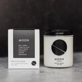 Moon candle with clear vessel and black writing black and white box.